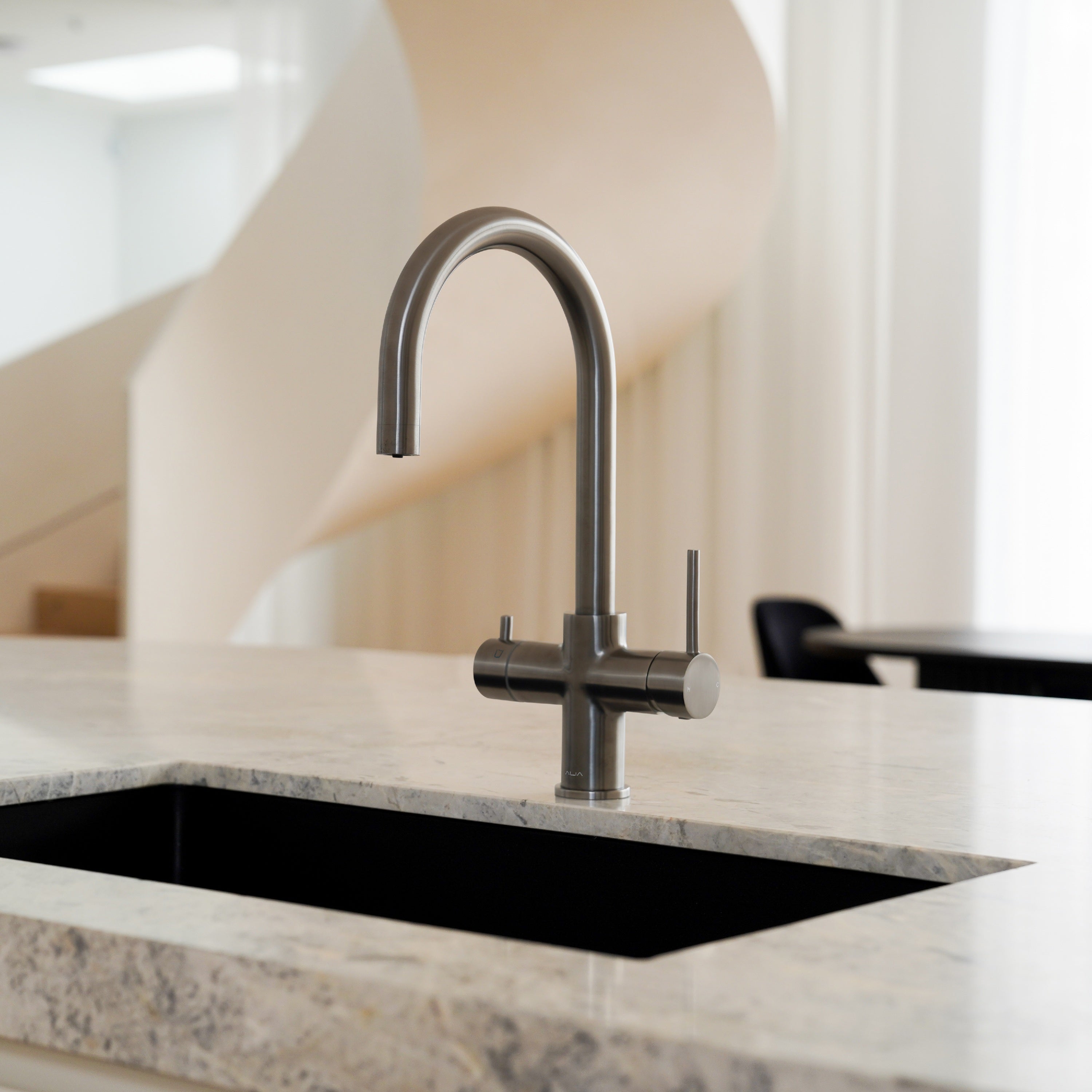 Gunmetal grey Alia Global 4-in-1 instant hot filtered water tap featured in a beautiful kitchen, offering filtered water and instant boiling water with sophisticated style.