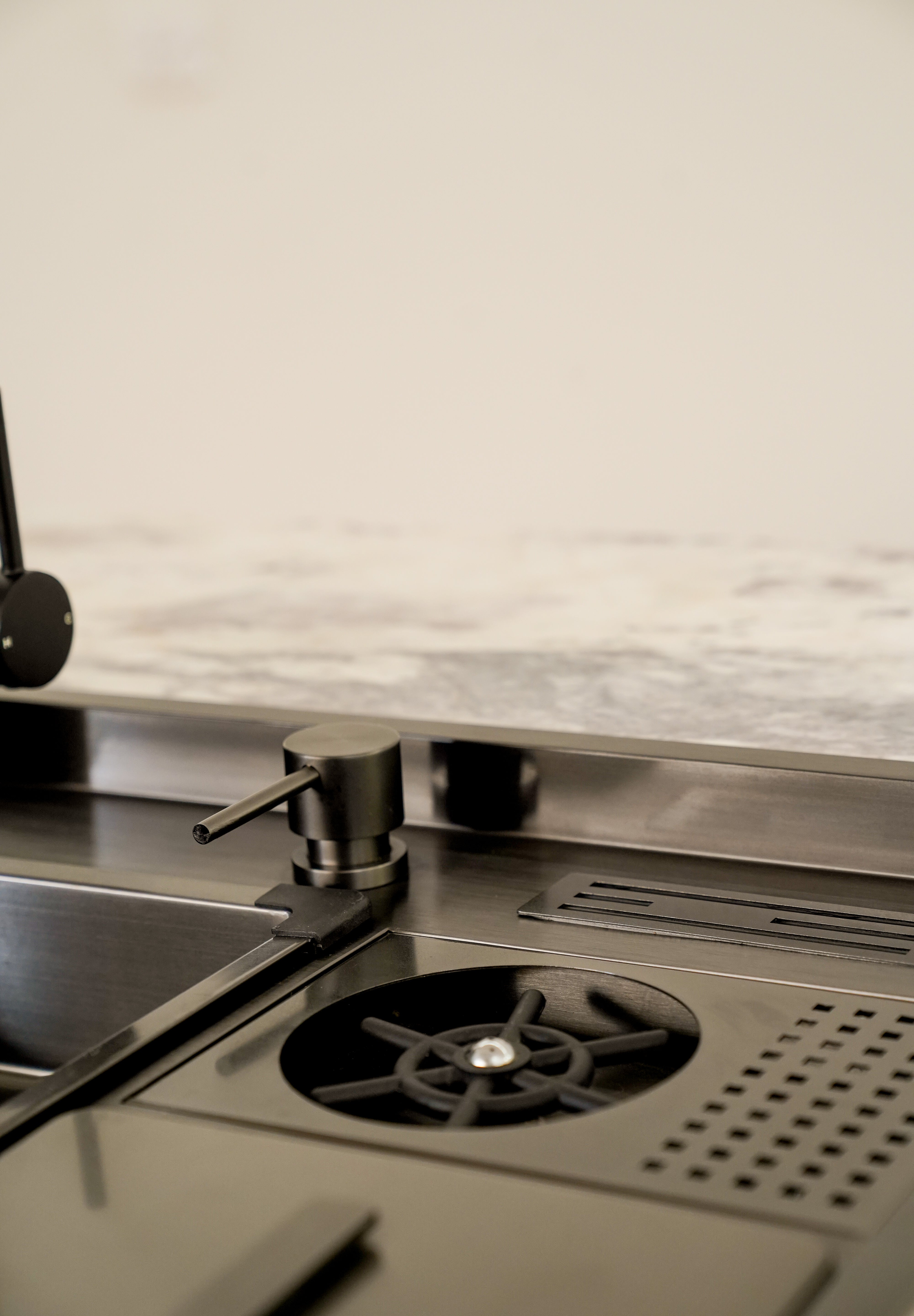 Elegantly designed ALIA Smart Sink displayed in a sophisticated kitchen, highlighting the integrated soap dispenser, high-pressure cup washer, compact waste bin, and knife rack with drain.