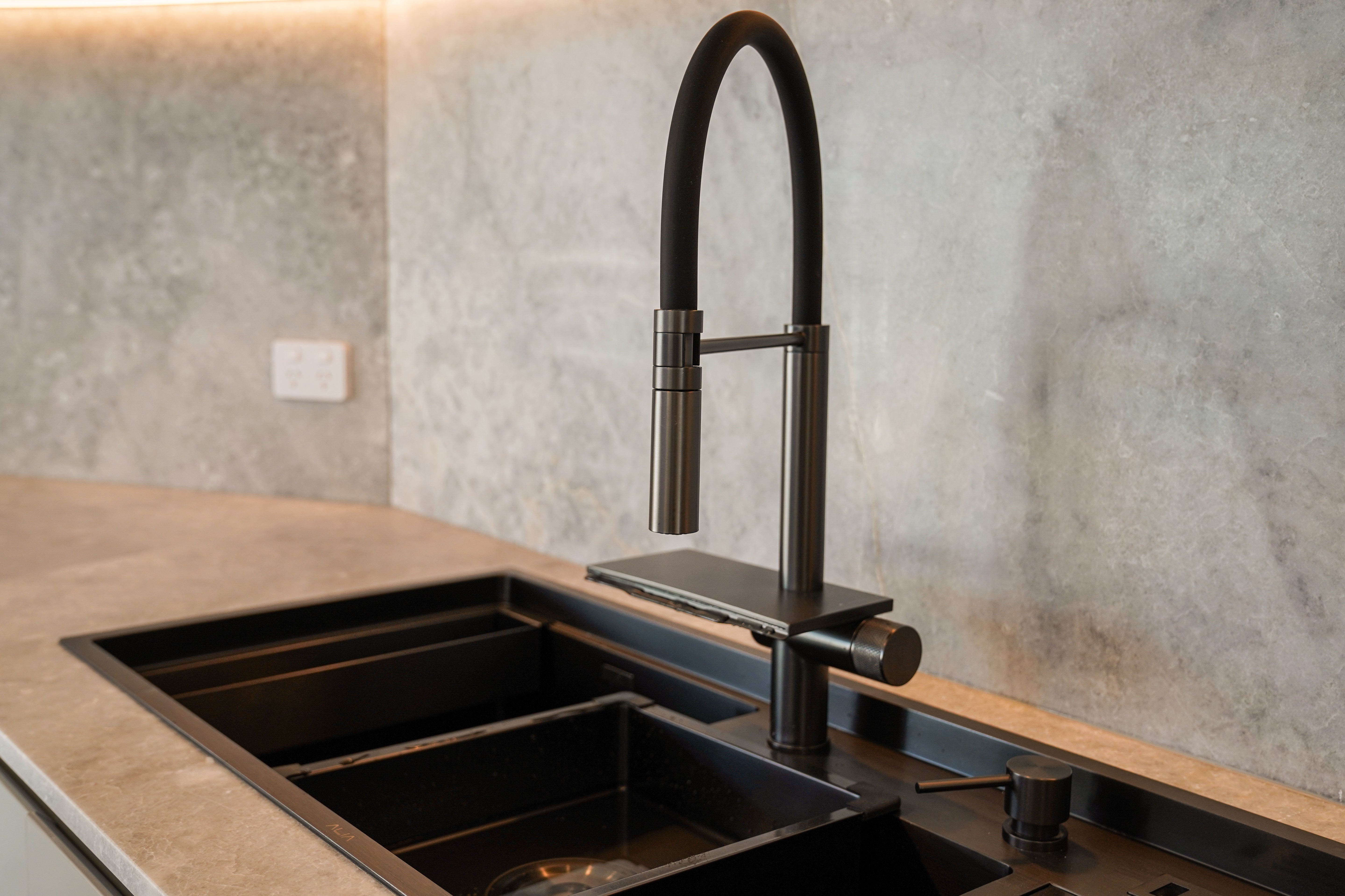 Modern kitchen scene featuring the ALIA Smart Sink with dual bowls, progressive 360° rotating pull-out mixer tap, and waterfall function for advanced usability and style.