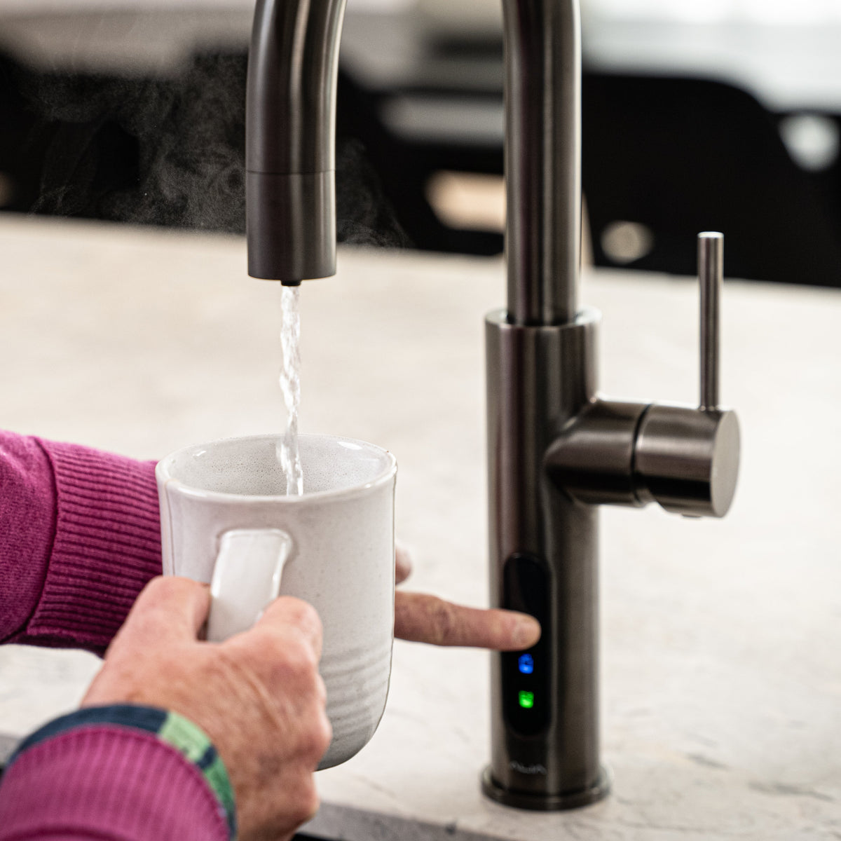 Person filling a white mug with water from a modern kitchen faucet.