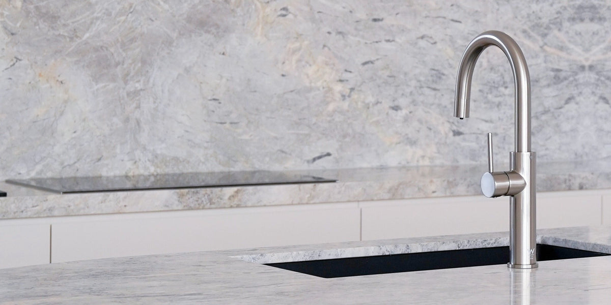 Marble finish hot, cold, and sparkling water dispenser on a marble background, showcasing a modern kitchen appliance for filtered water dispensing. This image highlights the versatile countertop drink dispenser in an elegant white and gray style.