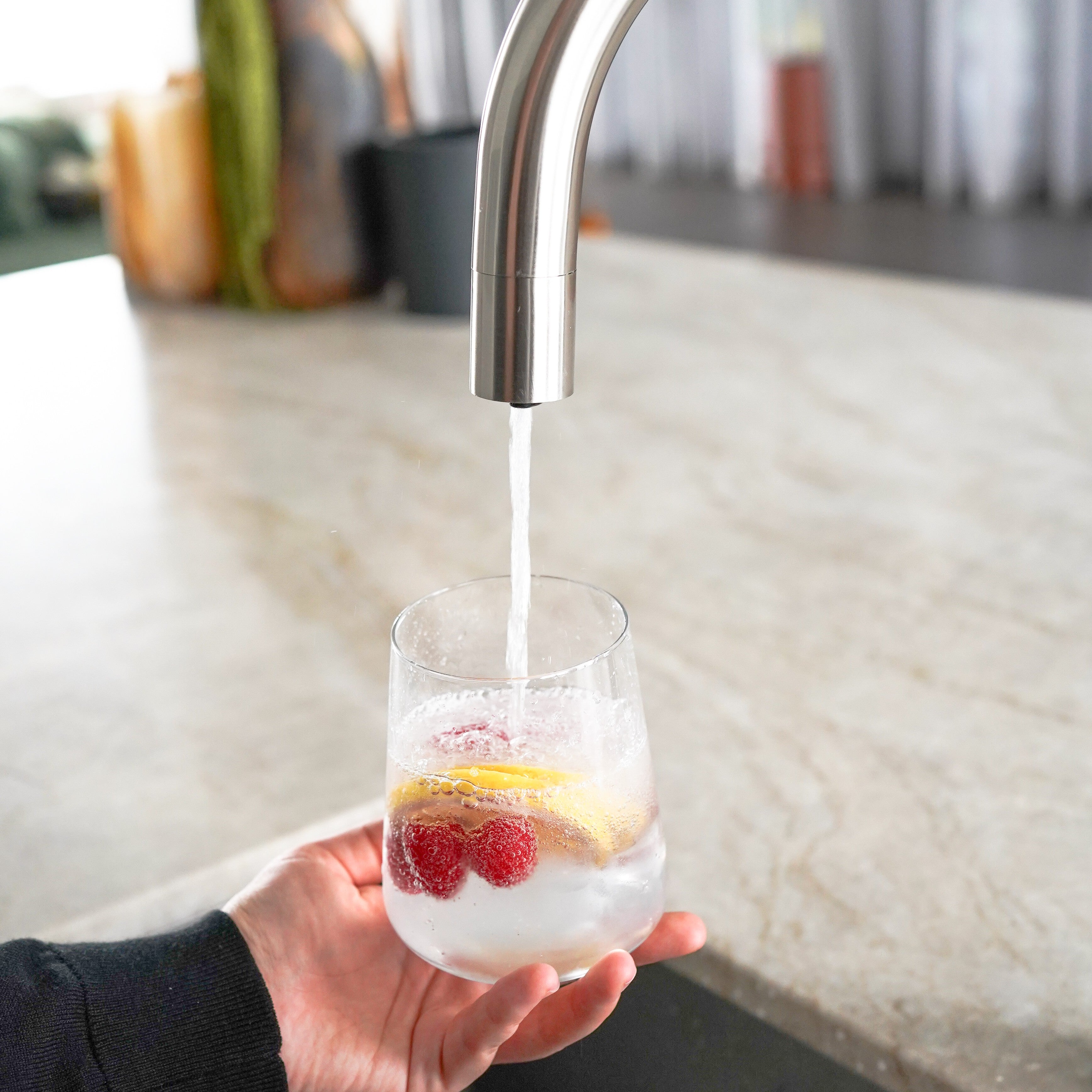 Alia X51 instant hot, cold, and sparkling filtered water tap in stainless steel dispensing sparkling water into a glass, showcasing a modern kitchen solution for fresh carbonated water on demand. This image highlights the convenience and versatility of the Alia X51 water tap, ideal for sparkling water lovers.