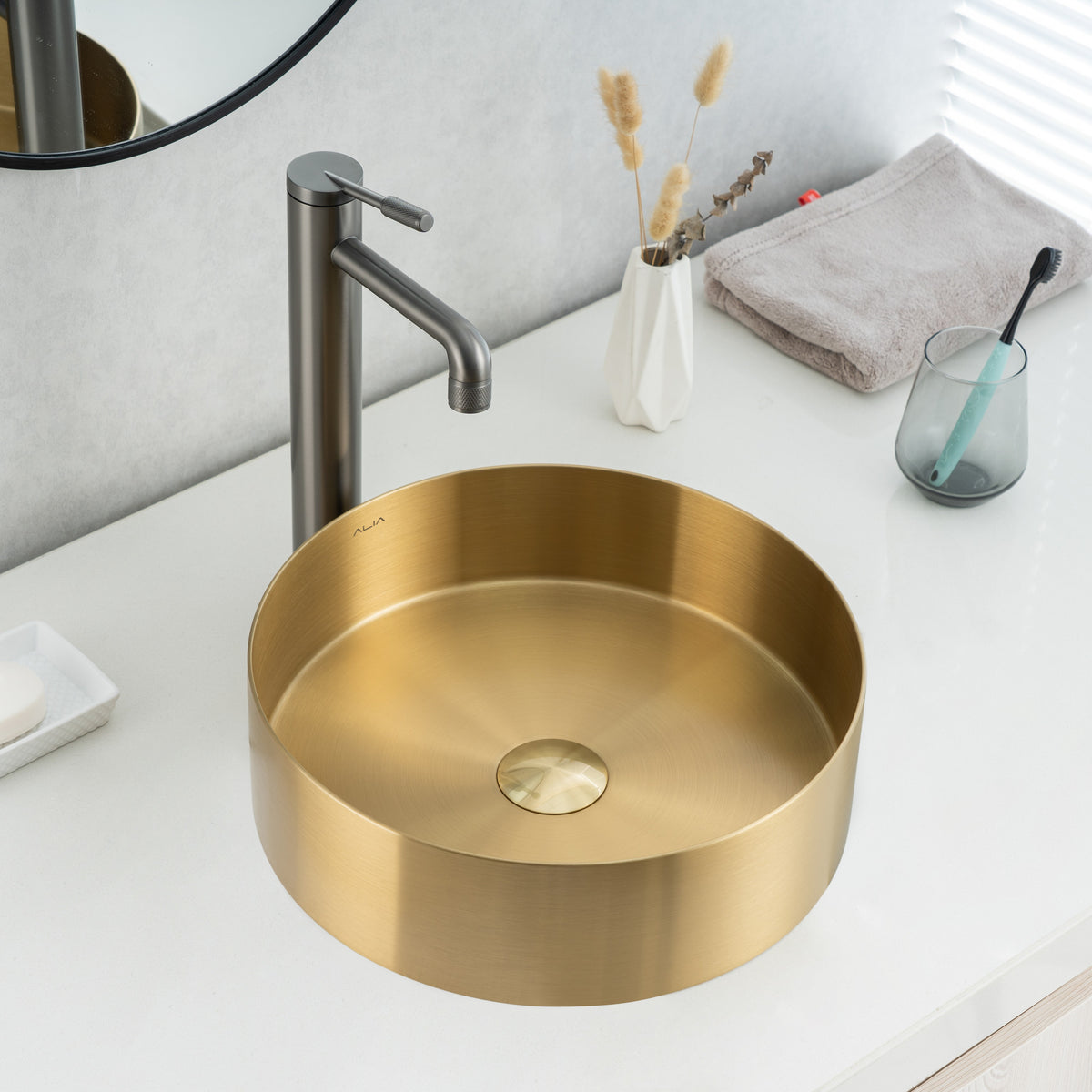 Real image of ALIA brushed gold round stainless steel basin installed on a modern vanity, highlighting its elegant metallic finish and above-counter design.