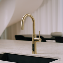 Alia X51 instant hot, cold, and sparkling filtered water tap in brushed gold finish, featured in a luxury kitchen setting, delivering pure filtered water with a touch of opulence.